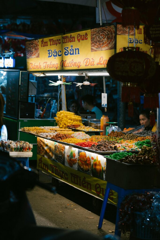 Illuminated Vietnamese food stall at a bustling night market, showcasing colorful delicacies.