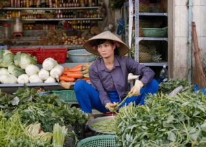 A vendor arranging fresh produce at a bustling market in Ho Chi Minh City, Vietnam.