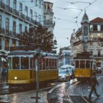 Scenic view of trams navigating the charming streets of Lisbon at dusk, capturing urban life and transportation.