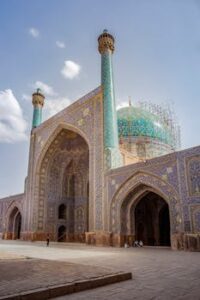 Explore the exquisite mosaic tiles and towering minarets of Shah Mosque, Isfahan, under bright sunlight.