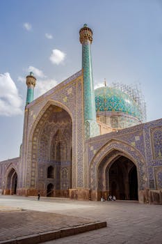Explore the exquisite mosaic tiles and towering minarets of Shah Mosque, Isfahan, under bright sunlight.