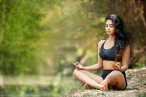 Woman practicing yoga in nature, peaceful meditation by a river.