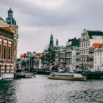 Charming canal scene in Amsterdam with historic architecture and a passing boat.